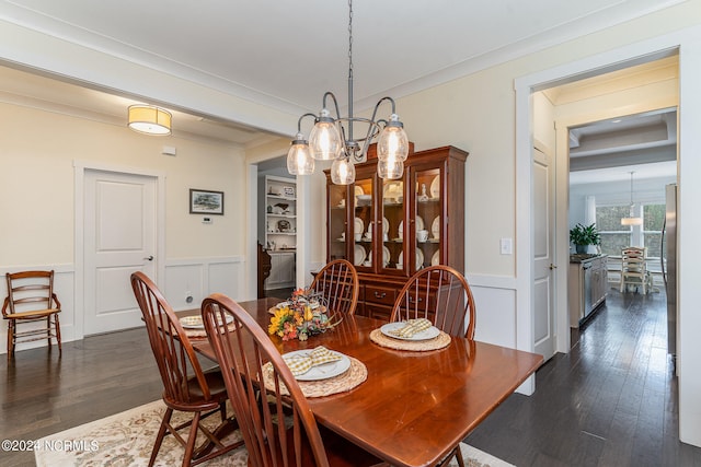 dining space featuring a notable chandelier, ornamental molding, and dark hardwood / wood-style flooring