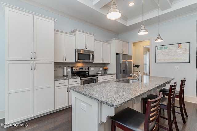 kitchen with appliances with stainless steel finishes, light stone counters, white cabinets, decorative light fixtures, and sink