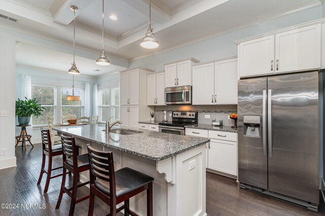 kitchen with white cabinets, a center island with sink, appliances with stainless steel finishes, and hanging light fixtures