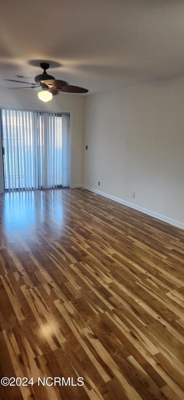 unfurnished room featuring ceiling fan, dark wood finished floors, and baseboards