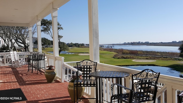 exterior space with covered porch, golf course view, and a water view