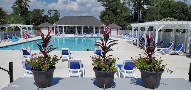 community pool with a patio area, fence, a pergola, and an outdoor structure