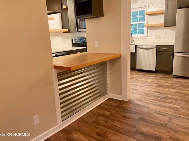 kitchen featuring dark brown cabinetry, wooden counters, light hardwood / wood-style flooring, backsplash, and appliances with stainless steel finishes