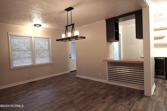 interior space with wine cooler, dark hardwood / wood-style flooring, pendant lighting, a textured ceiling, and ornamental molding