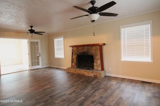 unfurnished living room with a textured ceiling, ceiling fan, dark hardwood / wood-style floors, and a stone fireplace