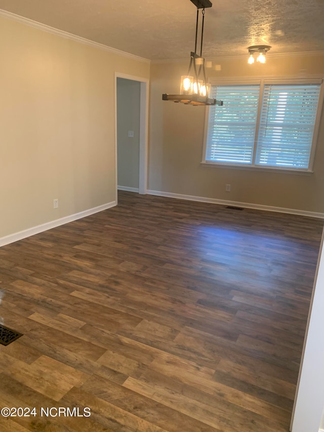 spare room with ornamental molding, a chandelier, a textured ceiling, and dark hardwood / wood-style flooring