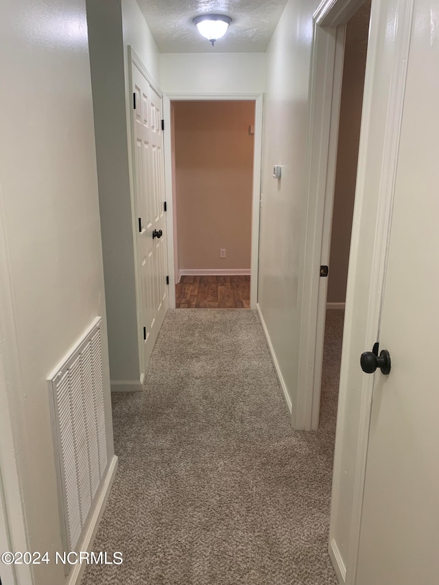 hall featuring carpet and a textured ceiling