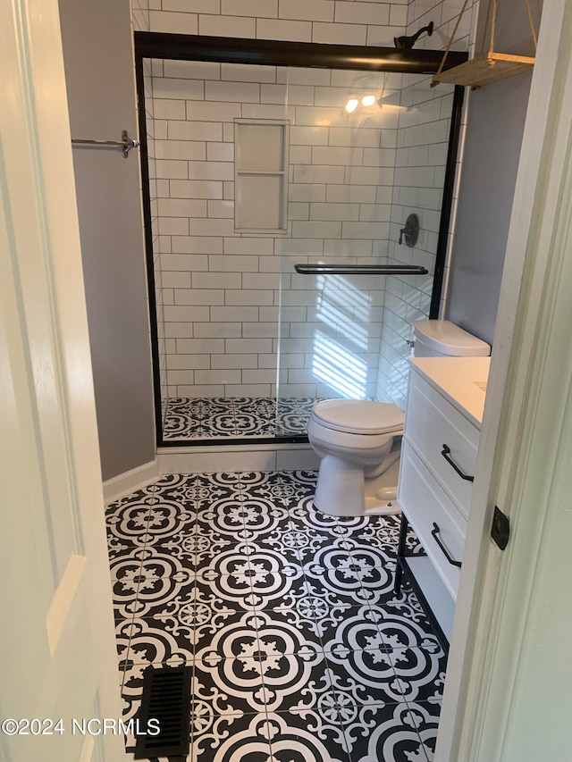 bathroom with tile patterned floors, walk in shower, vanity, and toilet