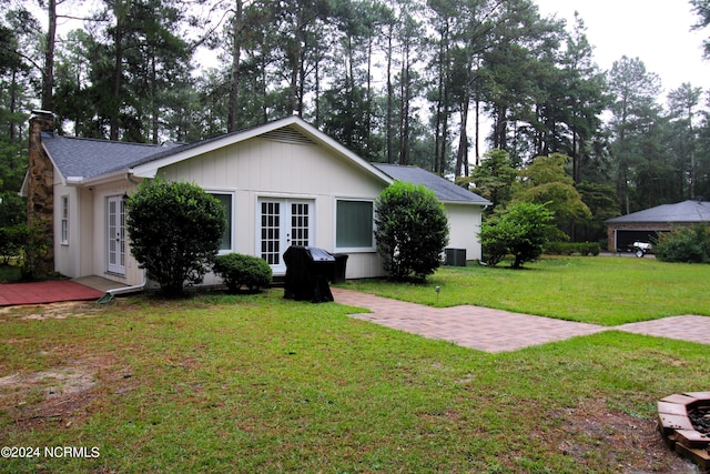 ranch-style home featuring a front lawn, central AC unit, and french doors