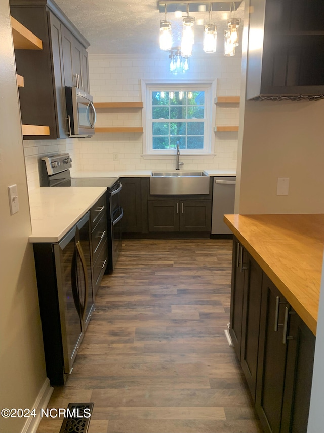 kitchen featuring appliances with stainless steel finishes, dark hardwood / wood-style floors, sink, and pendant lighting