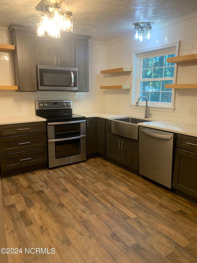 kitchen with pendant lighting, sink, a chandelier, stainless steel appliances, and hardwood / wood-style floors