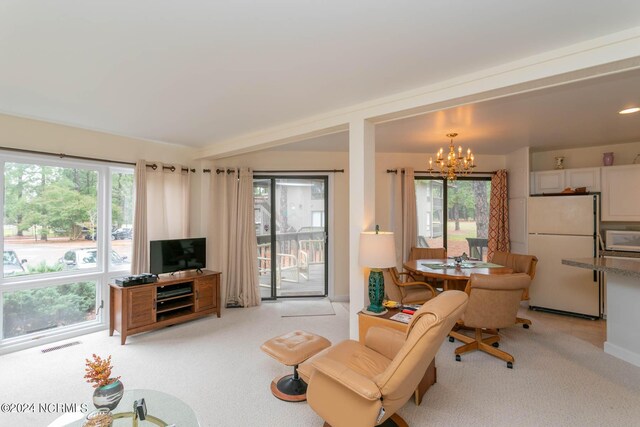 carpeted living room with an inviting chandelier and a healthy amount of sunlight