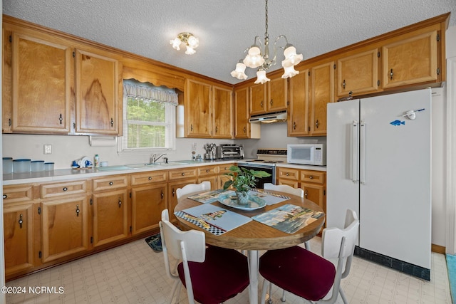 kitchen featuring sink, a textured ceiling, white appliances, and decorative light fixtures