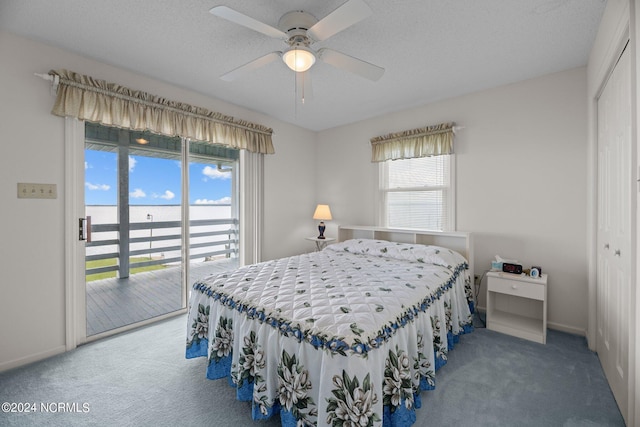 carpeted bedroom with ceiling fan, access to exterior, a water view, a textured ceiling, and a closet