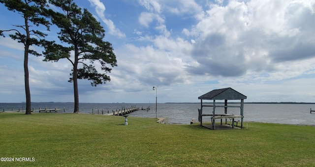 view of dock with a lawn and a water view