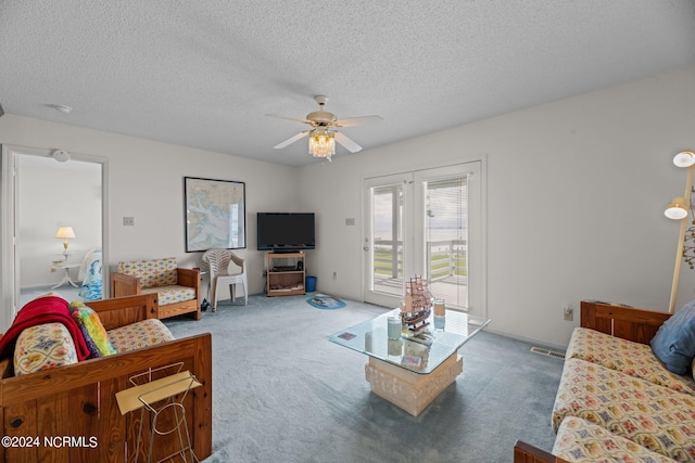 carpeted living room featuring ceiling fan and a textured ceiling