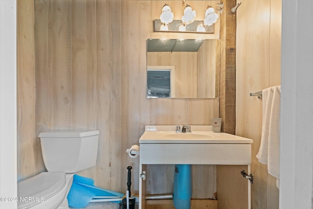 bathroom with toilet, wooden walls, and sink