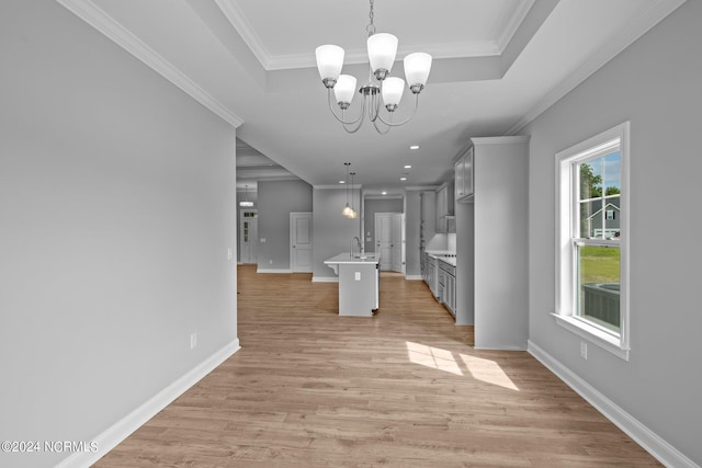 kitchen with a chandelier, a healthy amount of sunlight, decorative light fixtures, and a kitchen island with sink