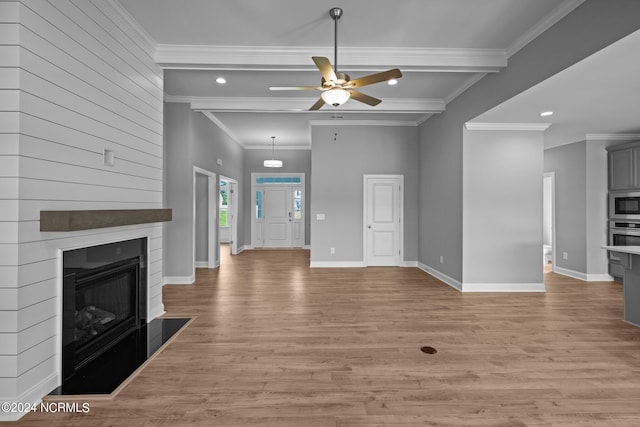 unfurnished living room with ceiling fan, light hardwood / wood-style floors, crown molding, and beamed ceiling