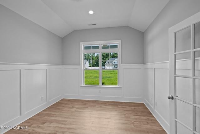 spare room featuring vaulted ceiling and light hardwood / wood-style flooring