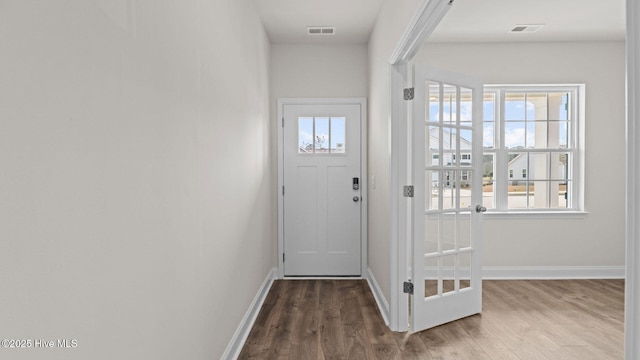 doorway featuring visible vents, baseboards, and wood finished floors