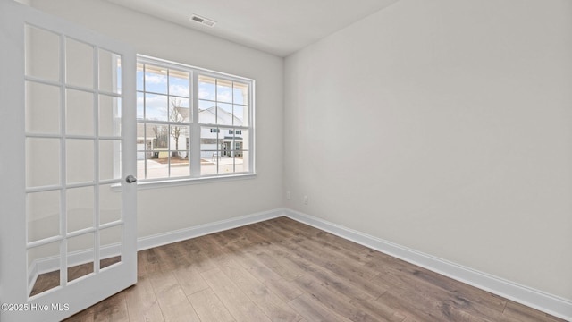 spare room featuring visible vents, baseboards, and wood finished floors