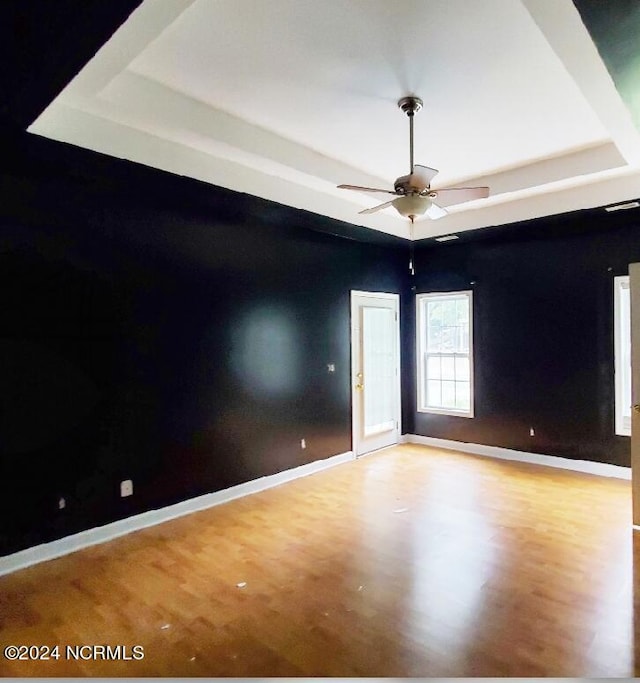 unfurnished room featuring a tray ceiling, ceiling fan, and light hardwood / wood-style floors