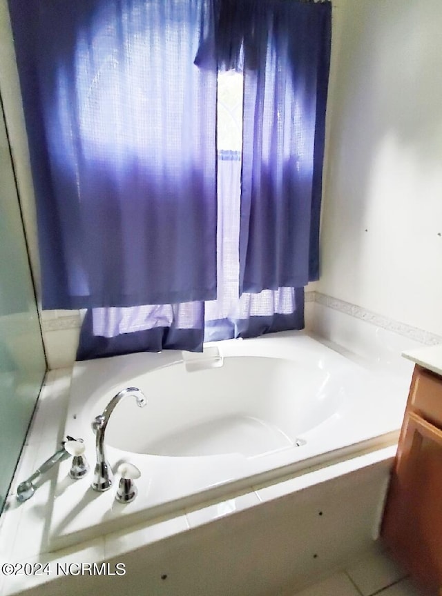 bathroom with tiled bath and vanity