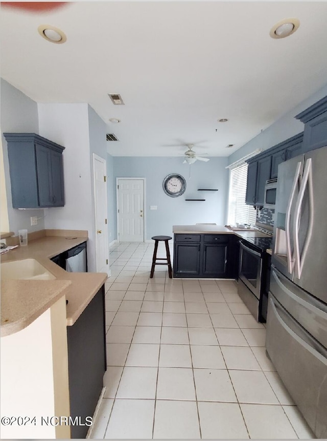 kitchen featuring appliances with stainless steel finishes, sink, kitchen peninsula, ceiling fan, and blue cabinets