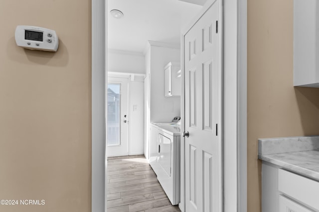 corridor with light hardwood / wood-style flooring, washer and dryer, and ornamental molding