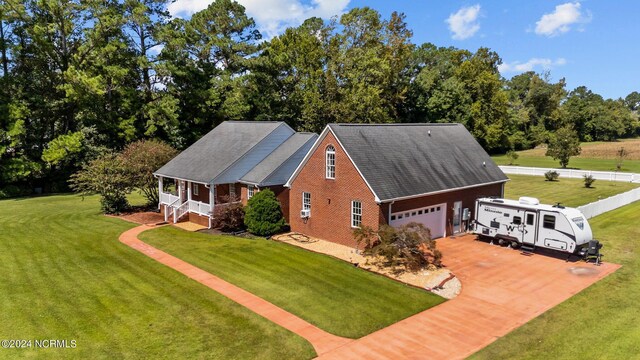 view of front of property featuring a garage, a front lawn, and covered porch