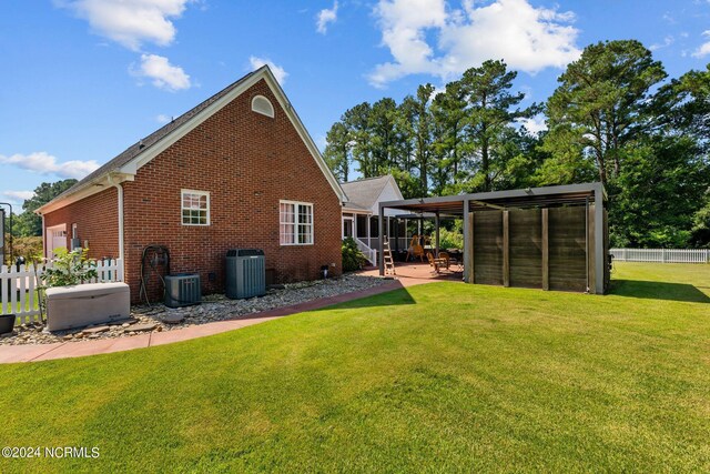 back of house featuring a lawn, cooling unit, and a patio area