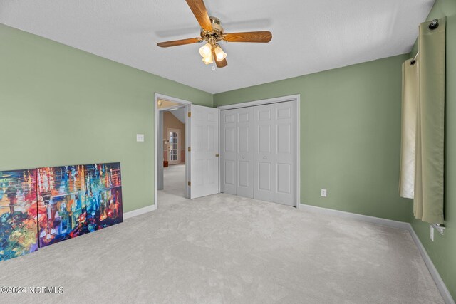 unfurnished bedroom with ceiling fan, a closet, and light carpet