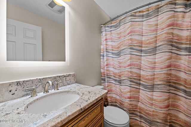 bathroom featuring a shower with shower curtain, vanity, and toilet