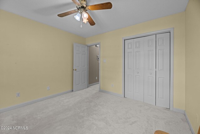 unfurnished bedroom featuring a closet, ceiling fan, and light colored carpet