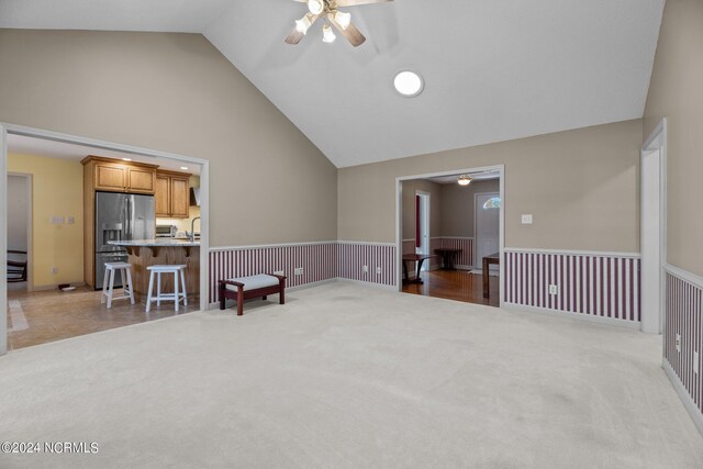 carpeted spare room featuring ceiling fan, sink, and high vaulted ceiling