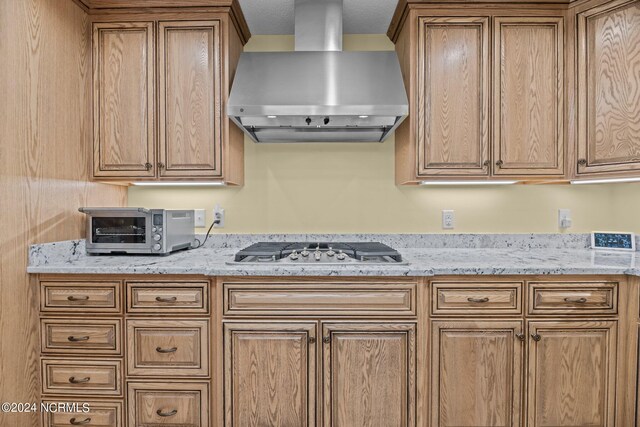 kitchen featuring stainless steel gas stovetop, light stone countertops, a textured ceiling, and wall chimney exhaust hood