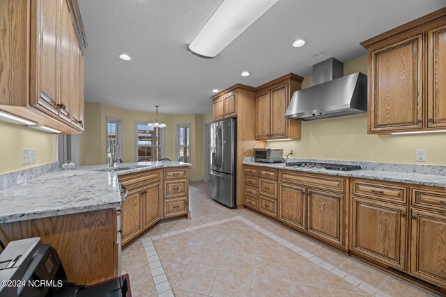 kitchen featuring appliances with stainless steel finishes, wall chimney exhaust hood, hanging light fixtures, and light tile patterned flooring