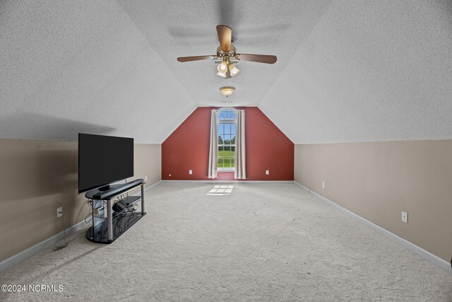 additional living space with vaulted ceiling, ceiling fan, carpet flooring, and a textured ceiling