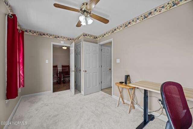 carpeted home office featuring ceiling fan