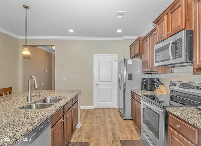 kitchen featuring sink, light stone counters, ornamental molding, pendant lighting, and appliances with stainless steel finishes