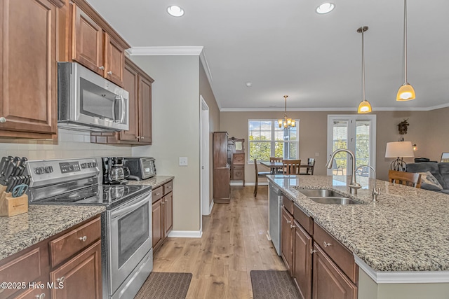 kitchen with appliances with stainless steel finishes, pendant lighting, a center island with sink, and sink