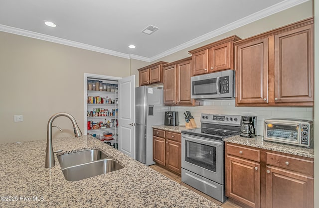 kitchen featuring appliances with stainless steel finishes, ornamental molding, light stone countertops, and sink