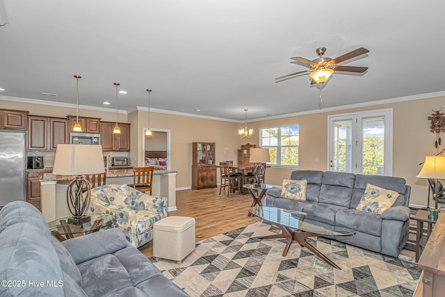 living room with ceiling fan with notable chandelier, light wood-type flooring, and ornamental molding