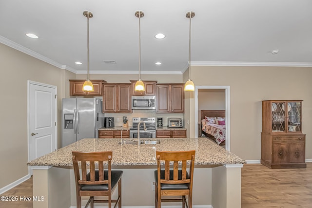 kitchen with a center island with sink, decorative light fixtures, and appliances with stainless steel finishes