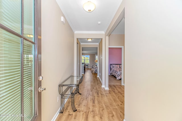 hallway featuring ornamental molding and light hardwood / wood-style flooring