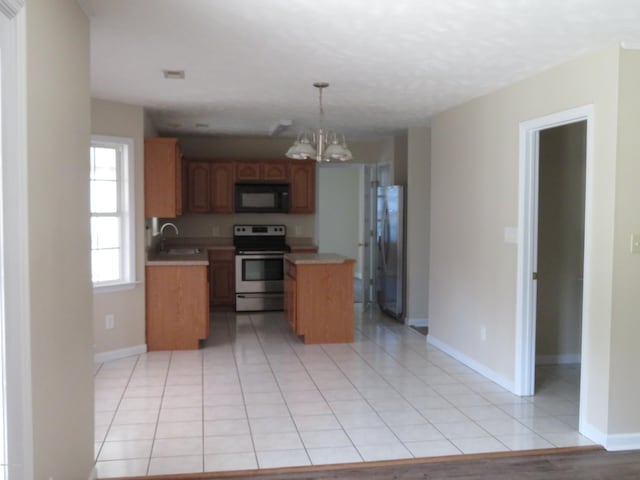 kitchen with white electric range, fridge, light tile patterned floors, a center island, and hanging light fixtures