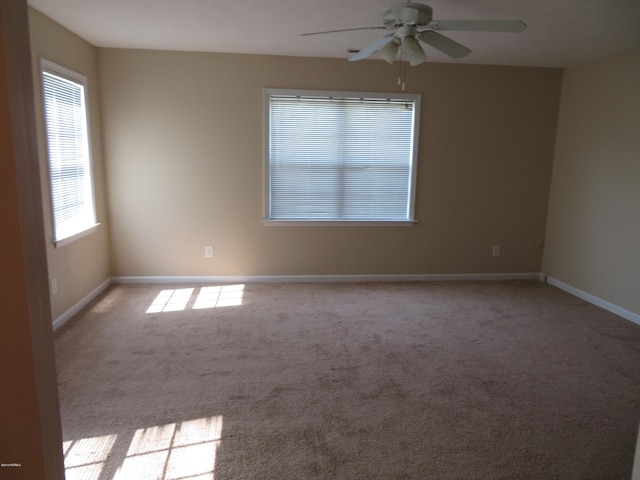 carpeted spare room with a wealth of natural light and ceiling fan