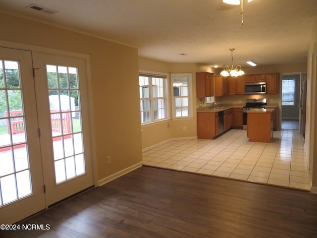 kitchen with light wood-type flooring, decorative light fixtures, appliances with stainless steel finishes, a notable chandelier, and a kitchen island