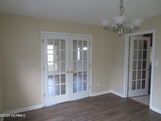 unfurnished dining area with an inviting chandelier, hardwood / wood-style floors, and french doors